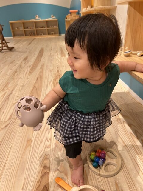 木の床の館内で、おもちゃを手にして遊ぶ子ども